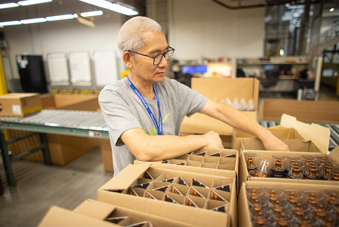 Bath & Body Works associate filling a cardboard box with products.